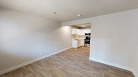This single-floor unit offers a clean, modern interior with a cohesive neutral color palette and light wood-look flooring that runs throughout the main living areas. The open living space is bright and functional, featuring crisp white walls, a textured ceiling, and a wall-mounted PTAC unit for climate control. A window at the front of the living area allows natural light to filter in, creating a welcoming atmosphere.

The kitchen is set slightly apart from the living area and is well-appointed with white shaker-style cabinetry, light countertops, and a stainless steel appliance suite that includes a refrigerator, electric range with overhead microwave, and a single-basin sink. The layout is efficient, making good use of the available space for both storage and meal preparation.

The bathroom is finished in a simple, clean style with a full tub and shower combination surrounded by white tile, a textured wall finish, a toilet, and a vanity with a mirror. The overall design is straightforward and functional.

Throughout the unit, the consistent use of light tones, updated finishes, and practical layouts contribute to a tidy, move-in-ready aesthetic that is both accessible and easy to maintain.