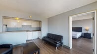 This two-bedroom, two-bathroom unit offers a practical and well-organized layout finished with hardwood-style flooring throughout. The open living area connects directly to a galley-style kitchen outfitted with white cabinetry, laminate countertops, a double sink, a dishwasher, and a range, providing ample storage and workspace for everyday cooking.

The living space accommodates both a seating area and a dining arrangement, with natural light filtering in through large windows fitted with horizontal blinds. A standout feature of the unit is the floor-to-ceiling windows found in both bedrooms, which frame city views and allow generous natural light to fill the rooms. Each bedroom offers comfortable proportions and hardwood-style flooring, with one bedroom benefiting from direct balcony access.

Both bathrooms are functional in design. One features an open vanity with a wide countertop and mirror, while the other includes a full tub-shower combination with teal tile surround, a toilet, and a single vanity. The neutral grey tones used throughout the unit create a cohesive and calm atmosphere, making the space feel clean and move-in ready.