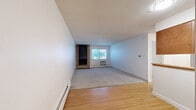 Located at 1301 30th St in Boulder, Colorado, this one-bedroom, one-bathroom residence offers a functional and well-appointed single-floor layout. The open living area is a standout feature, highlighted by a classic brick fireplace and a window that invites natural light and views of surrounding greenery. The space transitions seamlessly between hardwood flooring in the entry and kitchen areas and plush carpeting in the living and bedroom zones, adding warmth and texture throughout.

The kitchen is thoughtfully designed with rich wood cabinetry, white countertops, stainless steel appliances including a range, microwave, and refrigerator, and a window above the sink for added brightness. A peninsula counter connects the kitchen to the adjacent dining and living area, creating an efficient and cohesive flow.

The bedroom is a comfortable, carpeted retreat featuring a wide window with natural light, a wall-mounted AC unit, baseboard heating, and a large sliding-door closet. Additional closet space throughout the unit provides generous storage. The bathroom features a full tub-shower combination with white marble-style tile accented by a bold dark tile border, offering a clean and classic aesthetic. Baseboard heating is present throughout the unit, ensuring year-round comfort in Boulder's varied climate.