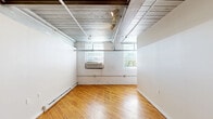 Located at 333 W Court St in downtown Allentown, PA, this two-floor unit blends industrial character with comfortable living across a well-appointed layout. Rich hardwood flooring runs throughout both levels, anchoring the space with warmth and continuity.

The main floor showcases a striking industrial aesthetic, highlighted by exposed wood-plank ceilings, steel beams, and track lighting. The kitchen is well-equipped with dark espresso cabinetry, granite countertops, black appliances including a range, microwave, and dishwasher, and a stainless steel sink — all set against the dramatic backdrop of the exposed ceiling. The living area on this floor features open sightlines, a structural column accent, and direct access to a hallway leading to additional rooms. A full bathroom on this level includes updated fixtures with light wood-tone flooring and a mirrored medicine cabinet.

The upper floor offers a more intimate atmosphere, with angled ceilings that lend architectural interest. Exposed painted brick walls and arched alcoves add historic character, while ceiling fans provide comfort throughout. Generous open rooms provide flexible living arrangements, each benefiting from the warm tones of the hardwood floors and ample natural light. A staircase connects the two levels, completing this distinctive and spacious multi-floor residence.