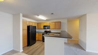 Located at 1201 Aragon Dr in Knightdale, NC, this single-story, 2-bedroom, 2-bathroom home offers a practical and comfortable layout designed for everyday living. The open-concept kitchen and living area forms the heart of the home, where warm oak cabinetry, dark granite-style countertops, and black appliances — including a range, over-the-range microwave, and refrigerator — are complemented by easy-care wood-look flooring. A peninsula counter with additional workspace provides a natural transition into the adjacent carpeted living room, creating a cohesive and functional shared space. The primary bedroom is generously sized, featuring plush carpeting, a ceiling fan with light, and natural light from windows with blinds. It connects directly to an en-suite bathroom equipped with warm wood vanity cabinetry, a full tub/shower combo, hardwood-style flooring, and mirrored medicine cabinets. The second bedroom also features carpet, a ceiling fan, and a window for natural light. The second full bathroom mirrors the primary bath's design with a tub/shower combination and a single vanity. A dedicated closet provides additional storage. Neutral tones and textured ceilings are consistent throughout, lending the home a clean, move-in-ready appeal.