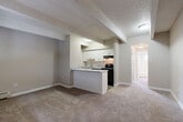 Located at 1082 S Dahlia St in Glendale, Colorado, this one-bedroom, one-bathroom residence offers a thoughtfully organized single-floor layout. The open-concept living area features wall-to-wall carpeting in neutral tones, exposed ceiling beams with a textured finish, and a seamless flow into the kitchen. The kitchen is efficiently designed with white cabinetry, light speckled countertops, a peninsula breakfast bar, wood-look vinyl flooring, and black appliances including a range, refrigerator, and dishwasher. A skylight above the kitchen adds a bright, airy touch to the cooking space. The bedroom is a comfortable, carpeted retreat featuring a wide window with blinds that invites natural light, a baseboard heater, and a sliding-door closet offering ample storage. A secondary closet or storage area is also accessible from the bedroom. The bathroom is clean and functional, finished with wood-look flooring, a full tub-shower combination, and a window providing natural ventilation. Neutral wall tones and consistent flooring materials throughout the space create a cohesive, understated aesthetic well-suited for comfortable everyday living.