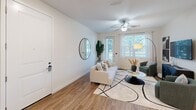 Located in Bonita Springs, Florida, this single-story 2-bedroom, 1-bathroom residence offers a thoughtfully designed open-concept layout filled with natural light. The living room features wood-look flooring, a ceiling fan, and large windows with views of lush greenery, creating a bright and airy atmosphere. It flows seamlessly into a dedicated dining area and a modern kitchen outfitted with white shaker cabinetry, granite countertops, stainless steel appliances, and a center island with bar seating illuminated by pendant lighting — ideal for both everyday cooking and casual entertaining. The primary bedroom is a comfortable retreat with plush carpeting, a walk-in closet with built-in shelving and drawers, and direct access to additional storage. The second bedroom also features carpeted floors and a large window that lets in ample natural light. The full bathroom includes a tiled tub-shower combination. Additional conveniences include multiple closets, a laundry area, a utility room, and a hallway connecting all spaces efficiently. The clean, neutral color palette throughout lends the home a cohesive and modern feel.