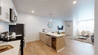 This well-appointed 2-bedroom, 2-bathroom residence offers a thoughtfully designed single-floor layout with modern finishes throughout. The open-concept kitchen serves as the centerpiece of the living area, featuring a large peninsula with seating for two, white quartz countertops, two-tone cabinetry combining white upper cabinets and warm wood-toned lower cabinets, a white subway tile backsplash, stainless steel appliances, and a built-in wine cooler. Pendant lighting and recessed lights illuminate the space, which flows seamlessly into the living area finished with light wood-tone flooring. The living room offers a comfortable, bright atmosphere with recessed lighting and access to the hallway leading to the bedrooms. Both bedrooms feature plush carpeting, ceiling fans, and windows that bring in natural light. The primary bedroom provides a generous footprint, while the second bedroom is well-suited as a guest room or home office. Each bathroom is finished with wood-toned vanities, white quartz countertops, wood-look tile flooring, and a shower-tub combination with marble-style tile surrounds. Two closets offer ample storage, completing this clean, contemporary residence.