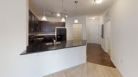 This single-floor residence is designed with a cohesive, neutral palette that creates a bright and welcoming atmosphere throughout. The kitchen serves as a central highlight, outfitted with rich dark espresso cabinetry, dark granite countertops, a tile backsplash, and black appliances including a refrigerator, range, and built-in microwave. A peninsula with pendant lighting provides additional workspace and connects seamlessly to the open living and dining area, which features plush carpeting, crown molding, and a dedicated pendant light fixture. Hardwood-style flooring runs through the kitchen, adding warmth and contrast to the darker cabinetry.

The bedrooms are carpeted and generously sized, each equipped with ceiling fans and walk-in closets fitted with built-in shelving and hanging rods for ample storage. Two full bathrooms are finished with tile flooring, white tub-shower combinations, and brushed nickel fixtures; one bathroom includes a dark vanity with an integrated sink and mirror. A dedicated in-unit laundry room accommodates a full-size washer and dryer side by side, with overhead wire shelving for additional storage. The overall layout is functional and well-organized, offering comfortable living across every room.