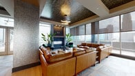 Located in the heart of uptown Charlotte at 500 W Trade Street, this elevated amenity floor delivers a refined, high-rise experience with panoramic views of the city skyline. The lounge area is a standout feature, anchored by generous leather sectional seating, a sleek fireplace, and a dramatic tray ceiling adorned with a richly patterned, dark wallcovering and a sculptural chandelier. Floor-to-ceiling windows wrap the space, flooding it with natural light and framing striking views of Charlotte's skyline. Adjacent to the lounge, a full catering kitchen features a broad dark countertop island, bold textured tile backsplash, professional-grade appliances, and distinctive barrel-shaped barstools with gold accents. A wine cellar with a glass-paned door adds an additional layer of sophistication. The formal dining and gathering area boasts a coffered white ceiling, dramatic brass orb chandeliers, a long communal table, and tan leather accent chairs — ideal for private events or social gatherings. Throughout, mixed flooring of large-format tile and warm wood planks unifies the varied spaces. The crown jewel is the outdoor rooftop pool deck, offering a refreshing pool and lounge area set against an impressive backdrop of Charlotte's urban skyline.