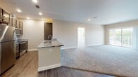 Located on Elm Street in Walpole, Massachusetts, this single-floor residence offers a thoughtfully designed open-concept layout finished with modern, high-quality details throughout. The main living area is generously proportioned, featuring plush wall-to-wall carpeting and an abundance of natural light streaming in through large double-hung windows that frame pleasant views of the surrounding neighborhood. Neutral-toned walls and crisp white trim create a clean, welcoming ambiance throughout the space. The kitchen is a standout feature, showcasing rich dark wood cabinetry, striking granite countertops with bold veining, a peninsula with an undermount sink, and a full suite of stainless steel appliances including a refrigerator, range, and over-the-range microwave. Durable hardwood-style flooring anchors the kitchen and adjoining areas. The primary bedroom suite is spacious, with carpeted floors, access to a walk-in closet, and a private en-suite bathroom finished with a granite-topped vanity, dark wood cabinetry, and tile flooring. A second bedroom, also carpeted and naturally lit, is served by a full hallway bathroom featuring a granite vanity, tub-shower combination, and coordinating tile floors. Recessed lighting throughout provides consistent illumination across all rooms.