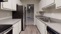 The St. Clair Premiere is a single-level, 2-bedroom, 2-bathroom residence designed with a practical and comfortable layout. The spacious living area is carpeted and filled with natural light, thanks to a large sliding glass door that opens onto a private balcony overlooking mature trees and greenery, providing a serene outdoor retreat. Vertical blinds and a curtain panel frame the balcony access, adding a functional design touch.

The galley-style kitchen features wood-look flooring, white cabinetry, gray laminate countertops, a stainless steel refrigerator, and matching appliances including a dishwasher and range. A ceiling fan is visible from the kitchen, providing air circulation to the adjacent bedroom area.

Both bedrooms are generously sized and carpeted, with one offering direct balcony access through a sliding glass door and tree views. Each bedroom includes closet storage. The two full bathrooms each feature a tub/shower combination with clean white surrounds, wood-look flooring, and neutral wall tones. Throughout the unit, a consistent neutral color palette and textured ceilings contribute to a cohesive, understated aesthetic.