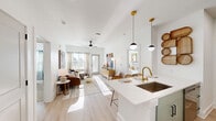 Located on Christopher Court in Arden, NC, this thoughtfully designed 2-bedroom, 2-bathroom residence offers a bright, modern living experience across a single floor. The open-concept layout seamlessly connects the kitchen, dining, and living areas, all finished with light wood-look flooring that enhances the airy, sun-filled atmosphere. The kitchen is a standout feature, boasting a quartz waterfall island with bar seating, gold-accented fixtures, a undermount sink, stainless steel appliances including a French door refrigerator and range, and light wood cabinetry accented by stylish pendant lighting. The living room flows naturally from the kitchen and opens to a private balcony, inviting natural light through large windows. Both bedrooms are carpeted and well-proportioned, each with ceiling fans and generous closet space. The primary bedroom connects to an en-suite bathroom featuring a dual-sink vanity with light wood cabinetry, gold hardware, and a glass-enclosed shower. The second bathroom offers a combination tub and shower. Additional conveniences include in-unit laundry, multiple hallways for smooth circulation, and ample closet storage throughout. The overall aesthetic is clean and contemporary, blending warm neutrals with modern gold and black accents.