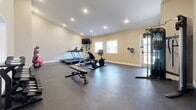 Located at 6444 Eden Garden Dr in Loveland, Colorado, this fitness center offers a well-equipped exercise space designed to support a comprehensive workout experience. The single-room facility features warm beige walls, recessed lighting, and durable rubber flooring throughout, creating a clean and functional environment.

The cardio area is outfitted with multiple treadmills and an elliptical trainer, complemented by a recumbent exercise bike, providing a variety of options for cardiovascular workouts. A wall-mounted flat-screen television is positioned for viewing during cardio sessions. For strength training, the space includes a multi-functional cable machine, an adjustable workout bench, and a full dumbbell rack with a range of free weights. Resistance bands and exercise balls round out the available equipment.

Natural light filters in through several windows, enhancing the bright and open atmosphere created by the recessed overhead lighting. The vaulted ceiling in one section of the room adds a sense of height and openness. The layout is thoughtfully arranged to allow ample floor space for movement and stretching. Overall, this fitness center delivers a practical and comfortable setting for residents to maintain an active lifestyle.