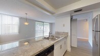 This single-floor residence offers a thoughtfully designed layout that balances open communal spaces with comfortable private areas. The living and dining area is anchored by light wood-tone flooring and neutral grey walls, creating a bright and airy atmosphere. A pendant light fixture adds a warm focal point, while a sliding glass door dressed with vertical blinds allows natural light to flow in and provides access to the outdoors.

The kitchen is efficiently designed with a galley-style configuration, featuring granite-patterned countertops, white cabinetry with brushed hardware, and stainless steel appliances including a range, microwave, and dishwasher. A peninsula with a double stainless steel sink connects the kitchen to the living area, reinforcing the open-concept feel.

The bedrooms are generously sized and finished with plush carpeting and soft grey walls. Each room benefits from natural light via vertical-blind-covered windows, and the primary bedroom includes dual closets with bi-fold doors, offering ample storage.

The bathroom is finished with white mosaic tile flooring, a vessel sink set atop a white vanity with a granite countertop, and clean, minimalist fixtures throughout. The overall design of this residence is clean, contemporary, and move-in ready.