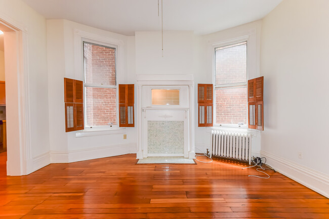 Large living room with refinished hardwood floors - 1617 W Grace St