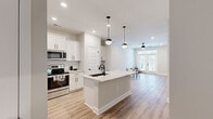Located at 9000 Palm Passage Loop in Summerville, SC, this single-floor, one-bedroom, one-bathroom home offers a thoughtfully designed open-concept layout that maximizes its well-proportioned footprint. Light hardwood-style flooring flows seamlessly throughout every room, lending a cohesive and contemporary feel.

The kitchen is a standout feature, showcasing white shaker cabinetry, a subway tile backsplash, stainless steel appliances, and a large central island topped with striking granite countertops. Globe pendant lights hang above the island, adding a modern aesthetic touch. A built-in desk nook off the kitchen provides a convenient workspace.

The open living and dining area is bright and airy, benefiting from a set of French doors that invite natural light and connect the interior to the outdoors. A ceiling fan completes the comfortable atmosphere of this space.

The bedroom is generously sized, featuring a ceiling fan, a window with natural light, and easy access to the hallway. The bathroom is finished with a white vanity with granite countertops, matching cabinetry, and black hardware accents consistent with the home's design language.

A dedicated laundry area with a washer and water heater adds practical convenience. The clean, neutral palette and modern finishes throughout make this home a polished and functional living space.