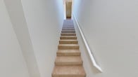Located at 1704 Tonini Dr in San Luis Obispo, California, this two-story home presents a thoughtfully arranged layout spread across two distinct levels. The interior is characterized by clean white walls and a bright, airy ambiance that lends a sense of openness throughout the space. A carpeted staircase connects the two floors, featuring warm neutral-toned steps framed by crisp white walls and a handrail, creating a simple yet functional transitional passage between levels. The overall design aesthetic leans toward a clean and understated style, with light tones dominating the interior palette. San Luis Obispo is well known for its desirable Central Coast climate, proximity to California Polytechnic State University, and its charming blend of outdoor recreation and community amenities, making this location particularly appealing. The home's two-floor configuration allows for a natural separation of living and private spaces, a practical and sought-after feature for comfortable everyday living. The consistent use of neutral finishes throughout contributes to a cohesive and inviting interior atmosphere.