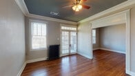 This two-bedroom, one-bathroom home in Memphis, Tennessee's 38104 zip code blends classic architectural character with practical updates throughout its single-floor layout. Rich hardwood floors run through the main living areas and bedrooms, complemented by crisp white crown molding and neutral gray walls that create a warm, cohesive aesthetic. The spacious living room is a standout, featuring elegant French doors with transom windows that invite abundant natural light and provide access to an outdoor area. A cast-iron radiator and ceiling fan add both charm and functionality to the room. The kitchen has been thoughtfully updated with white cabinetry, granite-look countertops, classic white subway tile backsplash, and a full suite of stainless steel appliances including a gas range, over-the-range microwave, and dishwasher. Both bedrooms offer generous proportions, hardwood flooring, ceiling fans, and large windows that fill the rooms with natural light. Cast-iron radiators in the bedrooms echo the home's period character. The bathroom retains its vintage appeal with white subway tile surrounding a soaking tub, hexagonal floor tile, and a wall-mounted sink. Throughout the home, paneled doors and detailed millwork speak to its enduring craftsmanship.