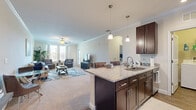 Located at 1124 Crosstown Way in Orlando, FL, this well-appointed one-bedroom, one-bathroom residence spans a comfortable single floor. The open-concept layout seamlessly connects the kitchen, dining, and living areas, creating an inviting, functional space. The kitchen is equipped with stainless steel appliances, rich dark-brown cabinetry, granite countertops, and a peninsula island with pendant lighting and bar seating — ideal for both cooking and casual dining. Wood-look flooring runs through the kitchen and entry hallway, while plush carpet lines the living room and bedroom. Crown molding adds a refined touch throughout the main living areas. The living room is bright and airy, featuring a ceiling fan and windows that let in ample natural light. The generously sized bedroom includes a walk-in closet with built-in shelving, windows with outdoor views, and carpeted flooring. The full bathroom offers a dark-wood vanity with granite countertops, wood-look tile flooring, and a tiled tub-shower combination. A dedicated in-unit laundry room with full-size washer and dryer adds everyday convenience. The space also includes a private balcony, a utility room, and a hallway that ties all areas together cohesively.