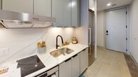 Located in the heart of Richmond, Virginia, this single-floor unit at 703 E Main St combines modern finishes with a warm, inviting atmosphere. The living area is a standout, featuring rich hardwood flooring, crisp white walls, and a large floor-to-ceiling window that floods the space with natural light while framing impressive views of the Richmond skyline and surrounding cityscape. The open layout flows seamlessly from the living area into the dining space, which showcases exposed beam accents, hardwood floors, and thoughtful decorative touches including a circular wall-mounted shelf nook.

The kitchen is sleek and contemporary, outfitted with flat-front gray cabinetry, white quartz countertops, a marble-style tile backsplash, an induction cooktop, stainless steel sink with a matte black faucet, and stainless steel refrigerator — all complemented by under-cabinet lighting for a polished finish.

The bedroom is bright and comfortable, with carpeted flooring, recessed lighting, and direct access to an outdoor space, allowing for additional natural light and fresh air. A dedicated laundry area features a stacked LG washer and dryer unit, adding everyday convenience. The overall design aesthetic is cohesive, modern, and carefully curated throughout.