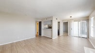 This single-story residence features 3 bedrooms and 2 bathrooms thoughtfully arranged across one level. The open-concept living and dining area is a welcoming centerpiece, highlighted by a classic white-mantled fireplace flanked by windows that allow natural light to fill the space. Light wood-look flooring runs throughout the main living areas, complementing the neutral warm-gray walls and textured ceilings.

The kitchen is efficiently designed in a galley configuration, featuring gray cabinetry with sleek hardware, a stainless steel refrigerator, and a suite of matching appliances including an electric range and dishwasher. A pass-through peninsula connects the kitchen to the main living area, enhancing the open feel. A sliding glass door provides additional access to natural light.

The bedrooms are carpeted for comfort, with the primary bedroom offering direct access to a walk-in closet with built-in shelving. A second closet features additional built-in storage. The secondary bedrooms are well-proportioned with windows and closet access. Both bathrooms are clean and functional, with one featuring a full tub-shower combination with tiled surround and wood-look flooring. A hallway connects the bedroom wing to the main living areas, completing this practical and cohesive floor plan.