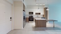 This well-appointed 1-bedroom, 1-bathroom residence at 4970 SW 124th Ave offers a thoughtfully designed single-floor layout with modern finishes throughout. The open-concept kitchen serves as the heart of the home, showcasing a two-tone cabinet design with white upper cabinets and warm wood-grain lower cabinets, a stainless steel appliance suite including a French door refrigerator, electric range, and built-in microwave, complemented by a sleek white countertop island with pendant lighting overhead. Track lighting and large format tile flooring carry throughout the main living areas, creating a cohesive and contemporary aesthetic. The bedroom is bright and comfortable, featuring a large window with a roller shade that frames lush, verdant outdoor views, filling the room with natural light. The bathroom includes a wood-toned vanity with a white countertop and a private water closet. A dedicated in-unit laundry closet with a stacked washer and dryer adds everyday convenience. Clean lines, neutral tones, and light wood-look flooring unify the space, delivering a modern, move-in ready residence.