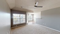 This thoughtfully designed 2-bedroom, 2-bathroom residence offers a comfortable and functional single-floor layout. The open living area is highlighted by plush neutral carpeting, a ceiling fan, and multiple large windows dressed with blinds that fill the space with ample natural light and views of the surrounding neighborhood. A pass-through counter connects the living area to the kitchen, enhancing the open flow of the floor plan.

The kitchen features white shaker-style cabinetry with brushed nickel hardware, granite countertops, a white subway tile backsplash, stainless steel appliances, and durable wood-look flooring — a clean and modern aesthetic ideal for everyday living.

Both bedrooms are generously sized and carpeted, with large windows — one showcasing a distinctive arched transom window — that bring in natural light. The primary bedroom includes a ceiling fan and a tray ceiling detail, adding an architectural touch to the space.

Each bathroom is equipped with a soaking tub and shower combination, accented by white tile surrounds with a decorative terracotta border, and wood-look flooring. The overall color palette throughout the residence features soft grays and neutral tones, lending a cohesive and contemporary feel to the entire home.