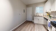 Located at 1000 Collier Rd NW in Atlanta's 30318 zip code, this 2-bedroom, 1-bathroom residence offers a practical and well-appointed single-floor layout. The living room features wood-look luxury vinyl flooring and neutral gray walls, creating a clean, modern atmosphere with access to the primary bedroom and bathroom. The combined kitchen and dining area is outfitted with white shaker cabinetry, granite-style countertops, stainless steel appliances including a gas range and refrigerator, and a stacked in-unit washer and dryer — maximizing functionality within a compact footprint. Natural light filters in through blinds-covered windows throughout. The full bathroom includes a tiled soaking tub and shower combination with a window for ventilation. Both bedrooms are carpeted and feature individual closets, with the second bedroom benefiting from dual windows and a ceiling fan. The primary bedroom includes a louvered closet door and direct access to the hallway. With four closets total across the unit, storage is well distributed. The neutral color palette, updated finishes, and efficient layout make this a comfortable and move-in ready home in Atlanta.