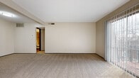 Located on E Kellogg Dr in Wichita, Kansas, this one-bedroom, one-bathroom unit offers a thoughtfully organized single-floor layout. The living room is a standout space, featuring large sliding glass doors dressed with vertical blinds that allow abundant natural light to fill the room and provide outdoor views. Neutral beige carpeting runs throughout the living and bedroom areas, complementing the warm, neutral-toned walls and creating a cohesive, understated aesthetic.

The bedroom is a comfortably sized private retreat, featuring a window that brings in additional natural light and a dedicated closet with a built-in hanging rod, offering practical storage. The kitchen is equipped with dark cabinetry, white appliances including a full-size refrigerator and dishwasher, and wood-look flooring that transitions cleanly from the carpeted areas.

The bathroom is well-appointed with wood-look flooring, white tile wainscoting, a gray vanity with a light countertop, and a tub/shower combination featuring large-format tile surround with a decorative mosaic accent border. The overall ambiance of the unit is clean, functional, and move-in ready.