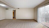 Located on E Kellogg Dr in Wichita, Kansas, this one-bedroom, one-bathroom unit offers a thoughtfully organized single-floor layout. The living room is a standout space, featuring large sliding glass doors dressed with vertical blinds that allow abundant natural light to fill the room and provide outdoor views. Neutral beige carpeting runs throughout the living and bedroom areas, complementing the warm, neutral-toned walls and creating a cohesive, understated aesthetic.

The bedroom is a comfortably sized private retreat, featuring a window that brings in additional natural light and a dedicated closet with a built-in hanging rod, offering practical storage. The kitchen is equipped with dark cabinetry, white appliances including a full-size refrigerator and dishwasher, and wood-look flooring that transitions cleanly from the carpeted areas.

The bathroom is well-appointed with wood-look flooring, white tile wainscoting, a gray vanity with a light countertop, and a tub/shower combination featuring large-format tile surround with a decorative mosaic accent border. The overall ambiance of the unit is clean, functional, and move-in ready.