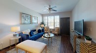 This two-bedroom, two-bathroom unit at Grand Courtyard is laid out entirely on a single floor, offering a cohesive and accessible living experience. The living room serves as the heart of the home, featuring rich wood-style flooring, a ceiling fan, and large windows fitted with blinds that allow generous natural light to fill the space. The open layout connects seamlessly to both the dining area and kitchen.

The kitchen is a standout feature, appointed with dark espresso cabinetry, granite-look countertops, stainless steel appliances, a double basin sink, pendant lighting, and an integrated wine rack above the upper cabinets. A breakfast bar provides additional counter space and casual seating. Adjacent to the kitchen, the dining area accommodates a full-sized table and offers access to an in-unit laundry space.

Both bedrooms are carpeted and well-lit by large windows, each equipped with ceiling fans. The primary bedroom includes a walk-in closet with built-in shelving. Each of the two bathrooms mirrors the kitchen's dark cabinetry and granite countertops, paired with full tub-shower combinations, large mirrors, and wood-style flooring, maintaining a consistent, polished aesthetic throughout the unit.