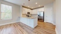 This 730-square-foot, one-bedroom, one-bathroom apartment at 150 Country Squire Dr in Cromwell, CT offers a clean, modern aesthetic with high-quality finishes throughout its single floor. The open-concept kitchen and living area serves as the heart of the unit, featuring light hardwood-style flooring, neutral walls, and abundant natural light. The kitchen is well-appointed with white shaker cabinetry, granite countertops, a subway tile backsplash, stainless steel appliances including a refrigerator with ice maker, electric range, and microwave, plus a central island with pendant lighting. The living room includes a ceiling fan, French doors, and multiple windows with blinds that provide outdoor views and natural light. The 170-square-foot bedroom features soft carpeting, a large window, and ample space, connected to the unit via a hallway with a dedicated closet for storage. The bathroom offers a clean, contemporary design with a subway-tiled tub/shower combo, hardwood-style flooring, and a vanity with brushed nickel hardware. The unit's consistent neutral palette and modern finishes create a cohesive, move-in-ready living environment.