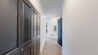 Located at 5130 W Expo Pkwy in Post Falls, Idaho, this single-floor unit offers four bedrooms and a combined kitchen and living area across a generously sized floor plan. The interior design follows a clean, modern aesthetic, with crisp white walls, light wood-style luxury vinyl plank flooring in the main living areas, and plush carpeting in the bedrooms.

The open-concept kitchen is well-appointed with dark-toned cabinetry, light countertops, and a full suite of stainless steel appliances, including a range, over-the-range microwave, dishwasher, and refrigerator. A peninsula provides additional counter space and separates the kitchen from the living area, which receives natural light through large windows fitted with vertical blinds.

A central hallway connects the bedrooms and features bold dark-paneled doors that add a striking contrast against the white walls. The bedrooms are bright and carpeted, with the primary bedroom offering a comfortable, well-proportioned layout. Secondary bedrooms include windows that bring in natural light. Closets feature dark double-panel bi-fold doors, maintaining the consistent design language found throughout the unit. The overall ambiance is clean, modern, and move-in ready.