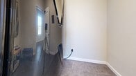 Located at 4001 De Morada Dr in Odessa, Texas, this single-floor space offers a thoughtfully arranged layout encompassing an exercise room, office, bedroom, laundry room, and connecting hallway. The standout feature is the expansive exercise room, which commands a significant portion of the floor plan. It showcases elegant tray ceilings with recessed lighting and ceiling fans, contributing to an airy, high-end atmosphere. Large windows along multiple walls flood the space with natural light, while durable rubber flooring provides a practical, professional-grade surface. Dark accent columns add a striking architectural contrast against the neutral cream-toned walls. A water station is conveniently built into the exercise area. The room comfortably accommodates a full range of cardio machines, strength equipment, free weights, and benches. A separate area within the layout appears designed for flexible use, such as a play or stretching zone. The office and bedroom offer more intimate, quietly finished spaces with tile flooring and clean, neutral walls. The laundry room and hallway provide functional connectivity throughout. Overall, the space maintains a polished, purposeful character well-suited for health and wellness-focused use.