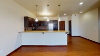 Located on Calico Drive in Fargo, North Dakota, this single-floor unit offers a well-designed, open-concept layout that blends functionality with comfort. The kitchen is a standout feature, appointed with rich dark cabinetry, a textured tile backsplash, stainless steel appliances including a refrigerator, range, and microwave, and a granite-topped island with bar seating. Pendant lighting and a chandelier add warmth and style to the space, while durable hardwood-style flooring extends throughout the kitchen and living areas, transitioning seamlessly to plush carpet in the living room. The bedrooms are comfortably sized with carpet flooring, ceiling fans, and ample natural light from large windows that offer views of the surrounding neighborhood. One bedroom features a sliding glass door, extending the sense of space. The bathroom is well-appointed with dark wood vanity cabinetry, stone-tile flooring, a full tub-shower combination, and a large mirror. A dedicated laundry room with a full-size washer and dryer adds everyday convenience. Additional storage is provided through a spacious walk-in closet with built-in wire shelving and a small window for natural light. Baseboard heating is present throughout, ensuring comfort during Fargo's colder months.
