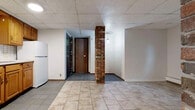 Located at 268 Alexander St in Rochester's East End neighborhood, this 2-bedroom, 1-bathroom unit offers a practical and efficiently organized layout across a single floor. The open kitchen-living area is anchored by a standout exposed brick column that adds architectural character to the space. The kitchen is equipped with warm oak cabinetry, a white tile backsplash, a gas range, refrigerator, and a sink with ample counter space — providing all essential cooking amenities in a compact, well-arranged footprint. Tile flooring runs throughout the unit, offering durability and easy maintenance. A drop tile ceiling is consistent across all rooms, keeping the interior uniform in style. The primary bedroom is a comfortable size and features a window that brings in natural light, along with a baseboard heating system. The second bedroom is similarly appointed with a window and baseboard heat, making it well-suited as a guest room or home office. The bathroom includes a full tub-shower combination, a vanity with storage, mosaic tile flooring, and partial tile wall accents. Additional storage is accessible via a closet near the entry. This unit offers straightforward, functional living in a well-connected Rochester location.