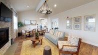 This single-story space is thoughtfully designed to blend functionality with a warm, inviting ambiance. The open layout connects several distinct areas that flow naturally into one another, creating a cohesive and comfortable environment.

The fully equipped kitchen serves as a central hub, featuring rich wood cabinetry, a decorative mosaic tile backsplash, stainless steel appliances including a gas range and French door refrigerator, and a generous island with a white countertop and bar seating. Pendant lighting and natural light from draped windows add to the welcoming atmosphere.

Adjacent dining areas offer multiple seating arrangements with sturdy wood tables and cushioned chairs. Soaring vaulted ceilings with exposed beams and a striking wrought-iron chandelier lend an airy, elegant feel to the dining and lounge space. A stone-accented fireplace anchors the living area, which is furnished with comfortable sofas and accent chairs arranged on a patterned area rug.

A dedicated coffee station with warm wood cabinetry, pendant lighting, and a round mirror adds a charming, functional touch. A quieter lounge nook, adorned with a vibrant triptych of abstract artwork, provides a relaxed retreat. Hardwood flooring and neutral tones throughout unify the space.
