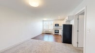 Located at 873 Harwich Road in Brewster, Massachusetts, this one-bedroom, one-bathroom unit offers a well-designed, efficient layout across a single floor. The open-concept living and kitchen area is defined by warm hardwood flooring, recessed lighting, and large windows that invite natural light throughout the space. The kitchen is thoughtfully appointed with white shaker-style cabinetry, granite countertops, a stainless steel refrigerator, stainless range, and built-in microwave — providing a clean, functional workspace. The living area transitions seamlessly from hardwood to plush carpeting, creating a comfortable and distinct zone for relaxation. The spacious primary bedroom features soft carpeting, a generous footprint, and direct access to a walk-in closet, offering ample storage. A second closet provides additional organizational convenience. The bathroom is finished with a full tub-and-shower combination, a granite-topped vanity, and a mirrored medicine cabinet, maintaining the consistent, modern aesthetic found throughout the unit. A wall-mounted HVAC unit ensures year-round climate control. The overall design is clean and contemporary, with a neutral palette of whites and soft grays that creates a bright, airy ambiance well-suited to the Cape Cod setting.