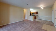 Located at 9001 SR-21 S in Port Wentworth, Georgia, this single-story residence offers a well-organized layout designed for comfortable everyday living. The galley-style kitchen is outfitted with warm wood cabinetry, granite-look countertops, hardwood-style flooring, and black appliances including a refrigerator, dishwasher, and range. A set of paneled bi-fold doors provides access to a pantry or utility closet, maximizing storage within the kitchen corridor.

The open living and dining area is finished with neutral carpet and warm beige walls, creating a bright and welcoming atmosphere. A ceiling fan anchors the dining nook, which benefits from a large window that draws in natural light and offers outdoor views. The layout flows seamlessly between the living space and the kitchen peninsula, which features additional cabinetry and track lighting overhead.

The bedroom is generously sized with plush carpeting, warm-toned walls, and a sliding glass door fitted with vertical blinds, allowing for natural light and outdoor access. The full bathroom is well-appointed with a granite-topped vanity, a large mirror, a tub-shower combination, and wood-look flooring that ties the space together cohesively. Throughout the unit, consistent warm tones and practical finishes contribute to a comfortable and functional living environment.