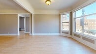 Located in Milwaukee's vibrant East Side neighborhood, this five-bedroom residence offers a thoughtfully arranged single-floor layout that balances classic architectural character with practical living. Hardwood floors run throughout the main living areas and bedrooms, lending warmth and continuity to the space. The living room serves as a welcoming centerpiece, highlighted by a decorative white-mantled fireplace, crown molding, and a charming bay window that floods the room with natural light and city views. Four connecting hallways guide residents through the home's well-organized floor plan. The spacious primary bedroom features large windows with urban views, while additional bedrooms offer closet space and natural light. The galley-style kitchen is equipped with white cabinetry, subway tile backsplash, dark countertops, a full suite of appliances including a dishwasher and gas range, and a window that invites in additional light. A cast-iron radiator adds a nod to the home's historic character. The full bathroom includes a tiled tub-shower combination and tile flooring. A dedicated laundry room with a full-size washer and dryer adds everyday convenience. Crown molding and clean white trim throughout reinforce the home's timeless aesthetic.