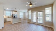 Located at 580 Creekside Way in New Braunfels, TX, this single-story residence offers a clean, modern design with a cohesive neutral palette and light wood-look flooring flowing throughout every room. The open-concept layout connects the kitchen and living area seamlessly, creating a bright and airy atmosphere enhanced by an abundance of natural light from multiple windows with blinds. French doors in the living area provide outdoor access and add an elegant touch to the space.

The kitchen is a standout feature, equipped with stainless steel appliances including a refrigerator with ice maker, dishwasher, range, and microwave. White shaker-style cabinetry, a classic subway tile backsplash, and a generous granite-topped island with pendant lighting make the kitchen both functional and visually appealing. A built-in desk area with open shelving and additional cabinetry offers practical workspace or storage options.

The bedrooms are well-proportioned, each featuring ceiling fans and natural light. The primary bathroom includes a tiled walk-in shower, a wide granite-topped vanity, and access to a spacious walk-in closet. The secondary bathroom offers a full tub-shower combo with brushed nickel fixtures and a matching granite vanity. Ceiling fans are present throughout, adding comfort and style to this well-appointed home.