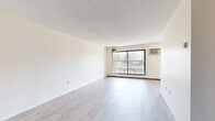 Located at 410 Van Dyke St in Saint Paul, MN, this one-bedroom, one-bathroom unit offers a well-organized single-floor layout with a clean, neutral aesthetic throughout. The combined kitchen and living area forms the heart of the unit. The living room is bright and open, featuring light wood-style flooring, a textured ceiling, baseboard heating, and a wall-mounted air conditioning unit. A large sliding glass door leads to a private balcony, filling the space with natural light and providing views of the surrounding neighborhood. The galley-style kitchen is efficiently designed with white cabinetry, ample upper and lower storage, a double-basin sink, gray laminate countertops, and white appliances including a range and refrigerator. The bedroom is carpeted and generously sized, equipped with a ceiling fan with light fixture, a window with blinds for natural light, baseboard heating, and access to two closets. The full bathroom features a classic white tile surround enclosing a soaking tub and shower combination, complemented by clean white fixtures. Two closets provide practical storage solutions throughout the unit. The overall ambiance is light, clean, and functional, making this a comfortable and practical living space.