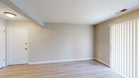 This single-floor unit at 16312 Hickory Pine Ln in Wildwood, Missouri offers a clean, well-maintained layout designed for functional everyday living. The interior is finished with neutral warm-gray walls and crisp white trim throughout, creating a cohesive and understated aesthetic.

The living areas feature light-toned hardwood-style flooring that extends through the main spaces, contributing to a bright and open feel. A sliding glass door fitted with vertical blinds allows natural light to filter into the living area while providing access to the outdoors. The layout, as visible in the floor plan, flows efficiently from the living space through a central corridor to the kitchen and bedroom areas.

The galley-style kitchen is well-appointed with white shaker cabinetry, brushed hardware, a marble-style tile backsplash, light countertops, and a full suite of stainless steel appliances including a range, dishwasher, refrigerator, and over-the-range microwave. Light wood-style flooring continues into the kitchen, maintaining visual consistency.

The bedrooms are carpeted in a warm tan tone, offering a comfortable contrast to the harder surfaces elsewhere. Windows provide natural light and outdoor views, while sliding closet doors open to roomy storage with built-in shelving and hanging rods. The overall ambiance is clean, neutral, and move-in ready.