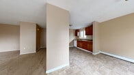 Located at 60 Grecian Gardens Dr in Rochester, NY, this two-bedroom, one-bathroom unit offers a practical and straightforward layout across a single floor. The combined kitchen and living area serves as the heart of the home, where rich, warm-toned wood cabinetry pairs with stone-look countertops and a tile floor. A window above the sink brings in natural light and frames an outdoor view, while ample upper and lower cabinet storage adds everyday functionality. A mosaic tile backsplash accents the cooking area, which includes a range with overhead ventilation.

The living area transitions seamlessly from the kitchen, featuring soft carpet underfoot and a neutral warm-beige color palette carried throughout the home. A wall-mounted air conditioning unit and baseboard heaters ensure year-round comfort. Both bedrooms are carpeted and well-sized, with the primary bedroom offering generous proportions, a large closet, and access to natural light. The second bedroom benefits from dual windows that offer outdoor views and ample brightness.

The full bathroom is finished with white square tile on the walls and surrounds the tub-shower combination, complemented by a window for natural ventilation. A connecting hallway ties the rooms together, creating an efficient and cohesive flow throughout the home.
