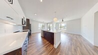 Located at 701 W Rio Salado Parkway in Tempe, Arizona, this single-floor residence offers a thoughtfully designed open-concept layout with modern finishes throughout. The kitchen serves as the centerpiece of the living space, anchored by a large island with a quartz countertop, an undermount sink with a matte black faucet, and a stylish globe pendant light overhead. Cabinetry features a two-tone design, pairing crisp white upper cabinets with rich dark wood lower cabinets, accented by black hardware. A white subway tile backsplash and stainless steel appliances — including a range, built-in microwave, and French door refrigerator — complete the kitchen. The open living area extends from the kitchen and is bathed in natural light through multiple windows offering outdoor views, complemented by wood-look flooring and a ceiling fan. The bedrooms continue the clean aesthetic with the same warm flooring, large windows, and ceiling fans. The bathrooms are finished with large-format tile flooring, dark wood vanities with white quartz countertops, matte black fixtures, and glass-enclosed walk-in showers with vertical tile surrounds. The primary bathroom includes a dual-sink vanity and access to a spacious walk-in closet with built-in shelving.