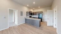 This single-floor, 2-bedroom, 2-bathroom home offers a functional and modern layout designed for comfortable everyday living. The open-concept kitchen serves as a central hub, featuring dark espresso cabinetry, granite countertops, a peninsula with an undermount sink, open shelving, and black appliances including a range, built-in microwave, dishwasher, and refrigerator. Light wood-look flooring flows throughout the main living areas, complemented by recessed lighting and a neutral color palette that creates a bright, cohesive atmosphere.

The living area is generously sized, featuring a ceiling fan and a sliding glass door with vertical blinds that allows for natural light and outdoor access. Both bedrooms are carpeted and offer a quiet, comfortable retreat. The primary bedroom includes direct access to a dedicated closet, while both closets are equipped with wire shelving systems for organized storage.

The bathrooms feature granite-topped dark wood vanities with mirrors, and the tub-shower combination is finished in clean white surrounds. A dedicated in-unit laundry area accommodates a full-size washer and dryer with overhead wire shelving. The entrance provides a welcoming transition into the home, completing a practical and well-rounded floor plan.