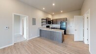This single-floor, 2-bedroom, 2-bathroom home offers a functional and modern layout designed for comfortable everyday living. The open-concept kitchen serves as a central hub, featuring dark espresso cabinetry, granite countertops, a peninsula with an undermount sink, open shelving, and black appliances including a range, built-in microwave, dishwasher, and refrigerator. Light wood-look flooring flows throughout the main living areas, complemented by recessed lighting and a neutral color palette that creates a bright, cohesive atmosphere.

The living area is generously sized, featuring a ceiling fan and a sliding glass door with vertical blinds that allows for natural light and outdoor access. Both bedrooms are carpeted and offer a quiet, comfortable retreat. The primary bedroom includes direct access to a dedicated closet, while both closets are equipped with wire shelving systems for organized storage.

The bathrooms feature granite-topped dark wood vanities with mirrors, and the tub-shower combination is finished in clean white surrounds. A dedicated in-unit laundry area accommodates a full-size washer and dryer with overhead wire shelving. The entrance provides a welcoming transition into the home, completing a practical and well-rounded floor plan.