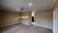 This two-floor home offers a functional and comfortable layout designed for everyday living. The main living area is open and spacious, finished with plush wall-to-wall carpeting that adds warmth underfoot. Crown molding frames the room elegantly, while recessed lighting and a ceiling fan provide both illumination and air circulation. Neutral-toned walls create a versatile backdrop throughout the space.

A defining feature of the main level is the kitchen pass-through counter, which opens the kitchen to the living area and promotes an easy flow between spaces. The kitchen is equipped with cabinetry and includes a full-size refrigerator, with tile flooring that contrasts the carpeted living areas. The pass-through bar-style counter offers additional utility as a casual dining or serving surface.

The layout extends across two floors, providing distinct zones for living and private spaces. The overall design is clean and straightforward, with consistent finishes that give the home a cohesive feel. Crown molding details and recessed lighting carry through the space, reinforcing a polished, well-maintained appearance. This home offers a practical and move-in ready environment suited for a variety of lifestyles.