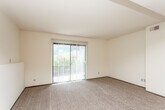 This single-floor residence offers a practical and well-organized layout designed for comfortable everyday living. The combined living and dining area is generously sized, featuring plush carpeting and a ceiling fan that anchors the space. A sliding glass door with vertical blinds fills the room with natural light and provides direct access to an outdoor view, enhancing the open feel of the interior.

The kitchen flows seamlessly from the living area and is finished with warm oak cabinetry, laminate countertops, wood-look vinyl flooring, and a white appliance suite including a range and dishwasher. A breakfast bar adds casual dining convenience and helps define the transition between the kitchen and living spaces.

The bedrooms are carpeted and bathed in natural light through standard windows fitted with horizontal blinds. Each room offers a clean, neutral palette with ample wall space for furniture placement. Closet access is visible in at least one bedroom.

The bathroom is straightforwardly appointed with a full tub-and-shower combination, a wood-look vinyl floor, a toilet, and a vanity with storage. Throughout the unit, textured ceilings, neutral cream walls, and dark baseboards provide a consistent and tidy aesthetic.