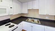 This single-floor unit offers a straightforward, functional layout with consistent warm-toned finishes throughout. The living area is spacious and open, featuring durable hardwood-style flooring that extends across the main living spaces. Neutral beige walls and a textured ceiling provide a clean, understated backdrop, while multiple windows allow natural light to fill the room, creating a bright and welcoming atmosphere.

The kitchen is efficiently designed with ample white cabinetry providing generous storage above and below the counter. Dark speckled countertops offer a contrasting visual element, and a double-basin stainless steel sink is conveniently positioned at the corner. A white range is included, rounding out the kitchen's functional setup.

The bedroom offers a quieter, cozier feel with plush wall-to-wall carpeting and neutral walls beneath a textured ceiling, providing a comfortable and private retreat.

The bathroom is clean and practical, featuring hardwood-style flooring that matches the main living areas, a full-size soaking tub with an overhead shower, chrome fixtures, and a window that introduces natural light. A towel bar and toilet complete the space.

Overall, this unit presents a cohesive, low-maintenance interior with consistent finishes and a functional flow between rooms suited for everyday living.