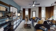 This thoughtfully designed single-floor residence offers a seamless open-concept layout connecting the kitchen, dining, and living areas into one cohesive, light-filled space. The kitchen is outfitted with white shaker cabinetry, quartz countertops, a teal subway tile backsplash, stainless steel appliances including a French door refrigerator and range, and a peninsula with an undermount sink — ideal for both cooking and casual entertaining. Pendant lighting and track fixtures add a contemporary touch throughout.

The dining area is bathed in natural light from multiple windows dressed in rich amber drapes, while the living room features hardwood-style flooring, a ceiling fan, and a glass door leading to the outdoors. Two bedrooms each carry a distinct character: one showcases textured grasscloth-style wallpaper and warm gold accents, while the second features a two-tone blue accent wall with a sleek metal bed frame.

The primary bathroom offers a dual-sink vanity with dark countertops, illuminated mirrors, and direct access to a spacious walk-in closet. A secondary bathroom provides large-format tile flooring and a glass-enclosed shower, completing this polished and functional residence.