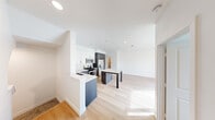 Located at 10785 Pomerado Road in San Diego, this three-story townhome offers four bedrooms and three bathrooms across a well-organized layout. The entry-level houses a private garage with an automatic opener, providing secure parking and additional storage space with a concrete floor and clean white walls.

The main living floor features an open-plan design where the kitchen flows seamlessly into the living and dining areas. The kitchen is equipped with stainless steel appliances, including a gas range, microwave, and French door refrigerator. White upper cabinetry contrasts with dark lower cabinets on the central island, which is topped with a light quartz countertop. Light hardwood flooring extends throughout this level, complementing the bright white walls and recessed lighting that create an airy, modern atmosphere. Natural light filters in through windows and a sliding door leading to a balcony.

The upper floor accommodates the bedrooms, including a primary suite, with plush carpet underfoot. Bedrooms feature windows with views of surrounding greenery. The bathrooms are finished in a contemporary style with dark wood vanities, white quartz countertops, round mirrors, and chrome fixtures, with one bathroom offering a full tub-shower combination.