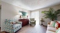 This well-organized one-bedroom, one-bathroom residence in Wichita, Kansas offers a thoughtfully designed single-floor layout that maximizes every square foot. The living room features rich wood-style hardwood flooring and a sliding glass door dressed with vertical blinds, allowing natural light to fill the space. A textured ceiling adds classic character throughout the common areas. Adjacent to the living room, the dining area is enhanced by a full-length wall mirror that amplifies the sense of space, and light tile flooring that carries through into the kitchen. The galley-style kitchen is equipped with white appliances, including a refrigerator, range, and dishwasher, complemented by gray cabinetry and a functional countertop workspace. The bedroom offers plush carpeting, a window with blinds, and a textured ceiling, providing a quiet and comfortable retreat. A dedicated closet and hallway offer practical storage and connectivity between rooms. The bathroom includes a tiled tub-shower combination, tile flooring, and a vanity with generous counter space. Overall, this residence presents a compact yet complete layout suited for efficient, comfortable everyday living.